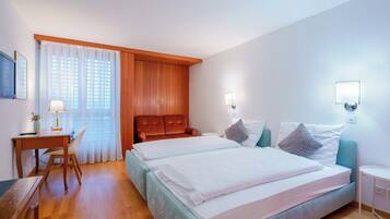 A hotel room with a bed, a desk, a chair, and a window with curtains.