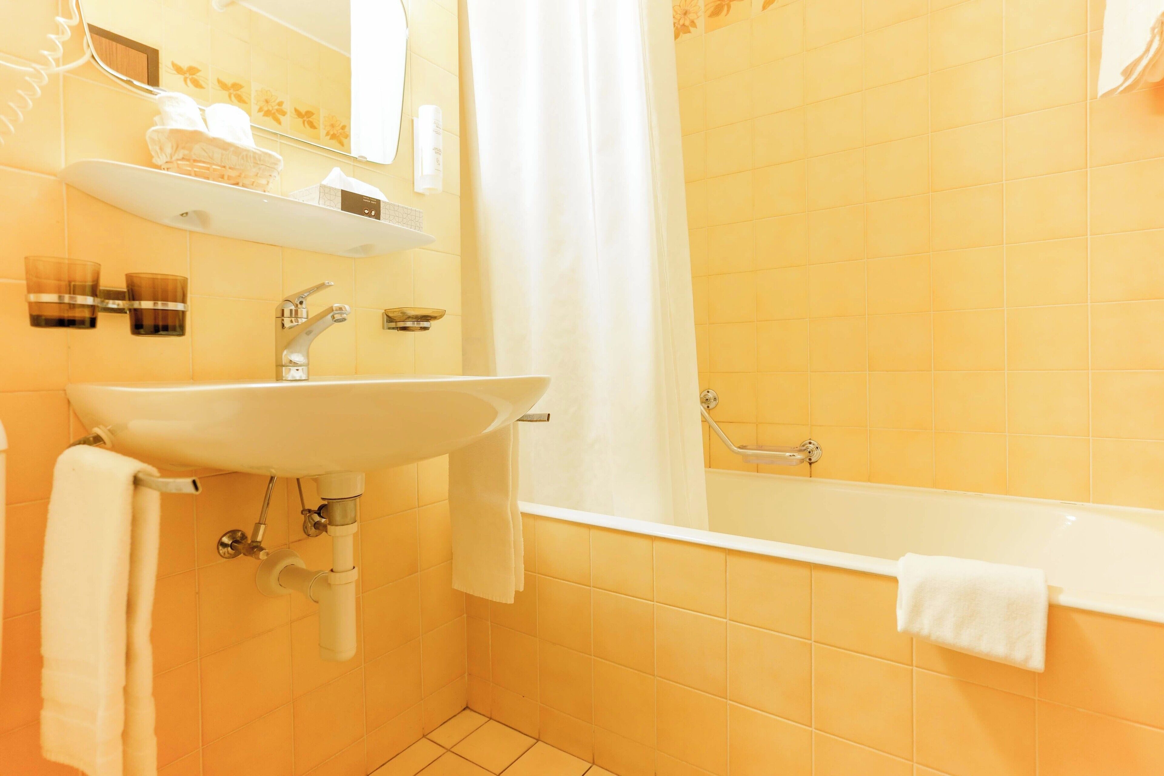 Un baño con lavamanos, espejo y bañera.