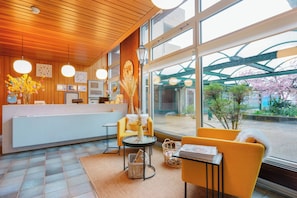 Uma área de recepção moderna com teto de madeira, janelas amplas e balcão de atendimento.