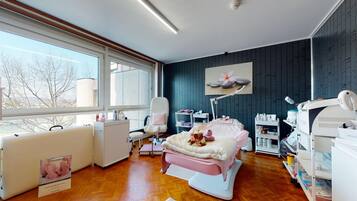 Una habitación médica moderna con una cama, mesa de exploración y diverso equipamiento médico.