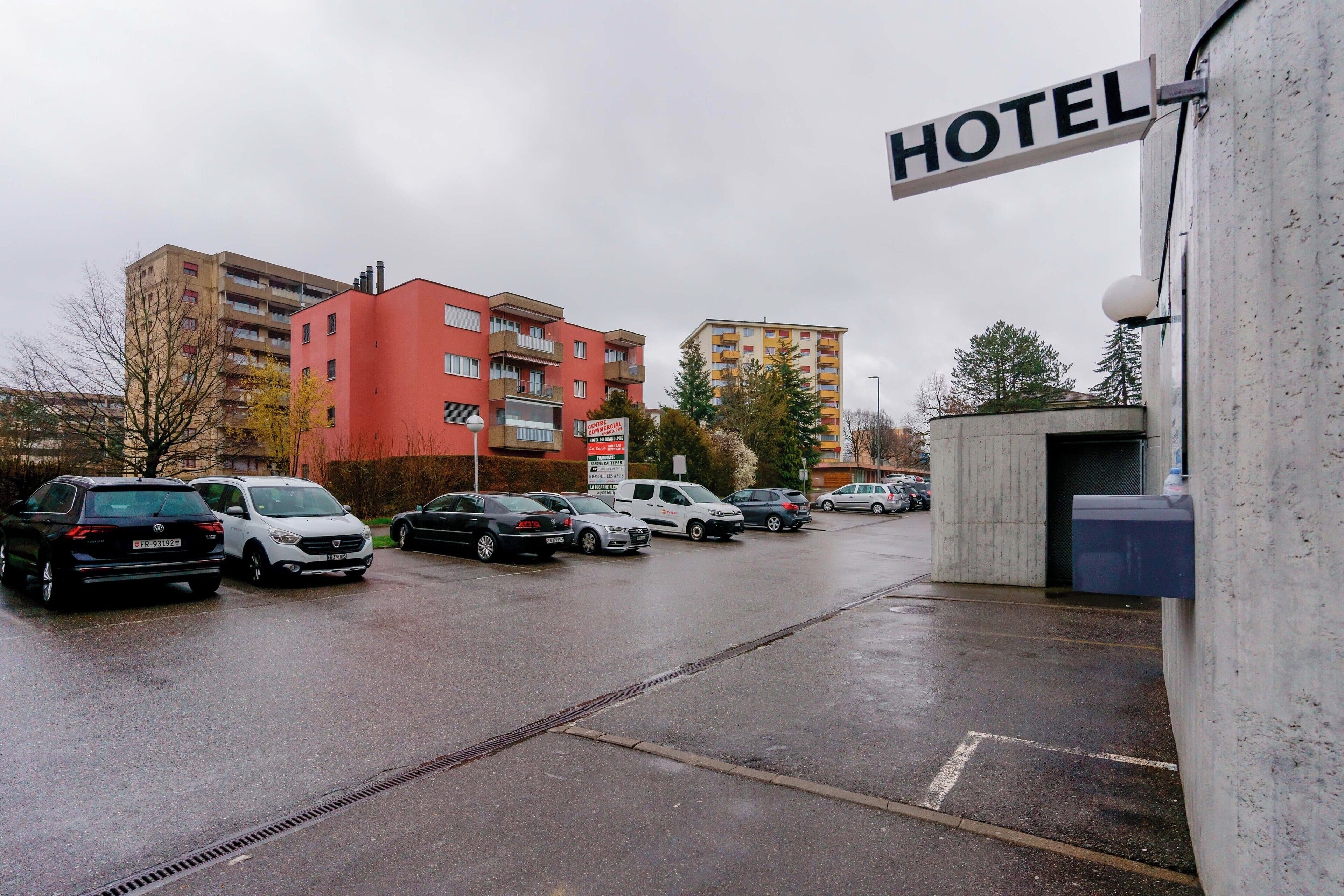 Ein Hotelparkplatz mit mehreren Autos und einem Schild, das den Namen des Hotels zeigt.