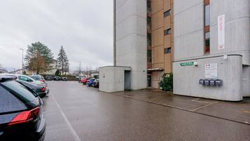 A hotel entrance with a concrete facade, a sign indicating a medical group, and a parking lot with cars.
