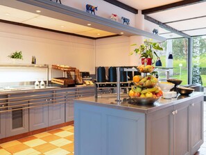 A modern kitchen with a central island, a coffee machine, and a fruit bowl. - ibis budget Geneve Aeroport (Vernier)