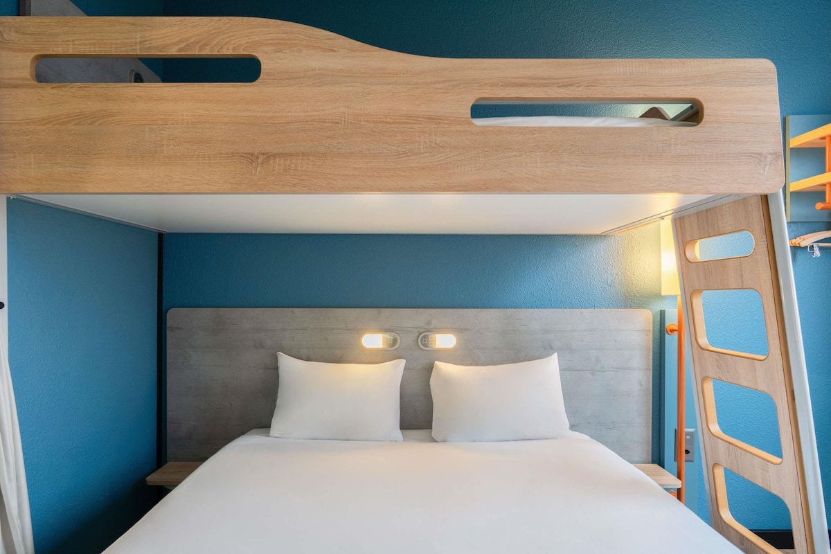 Uma cama beliche com cabeceira de madeira, duas luminárias de mesa e uma mesa de cabeceira.