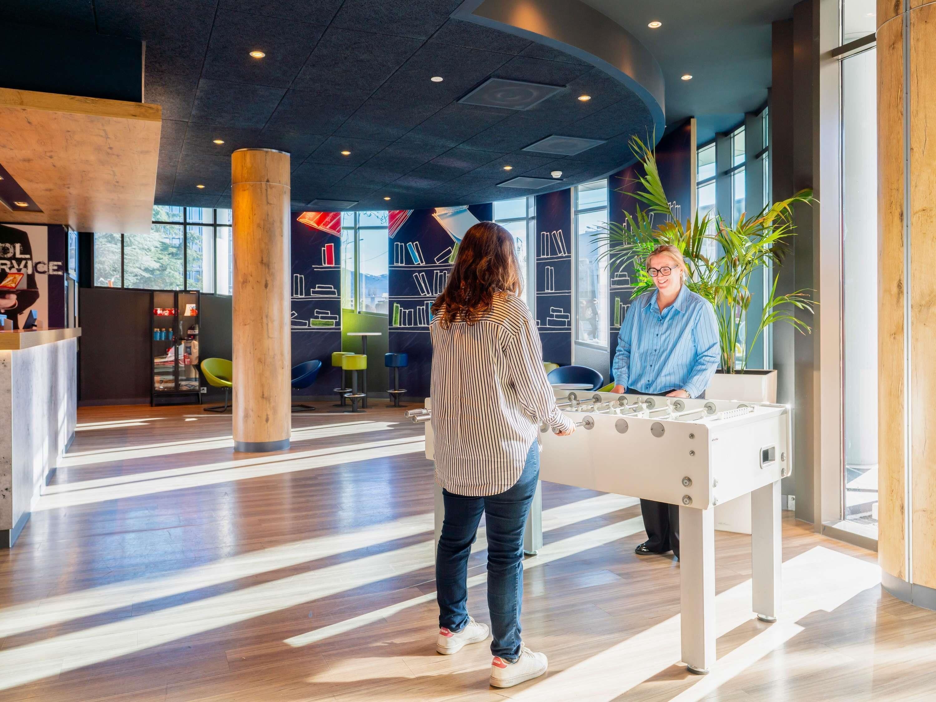Eine moderne Lobby mit einer Tischfußballplatte, Sitzbereichen und einem großen Fenster mit Blick.