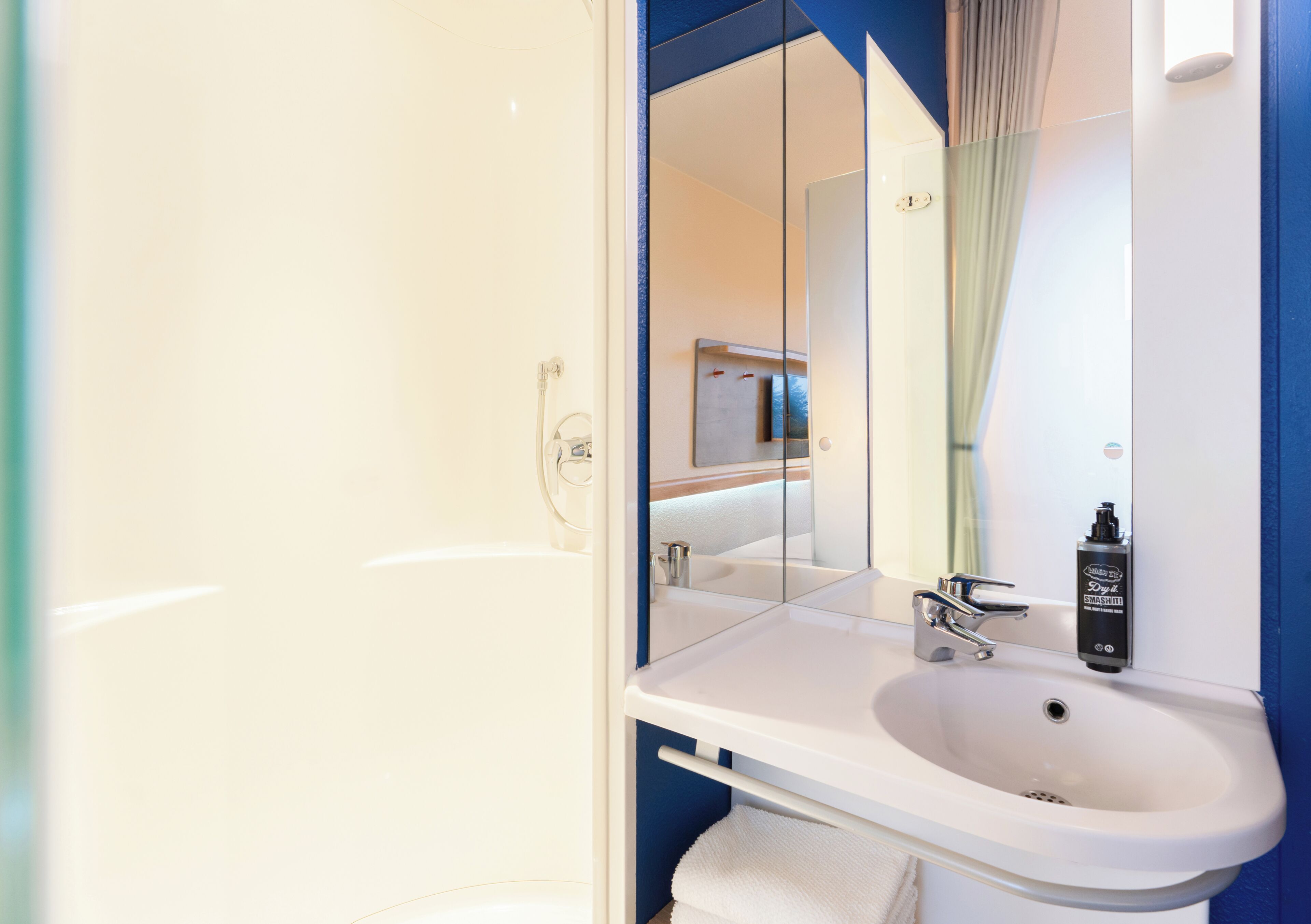 A bathroom with a white sink, a mirror, and a shower area.