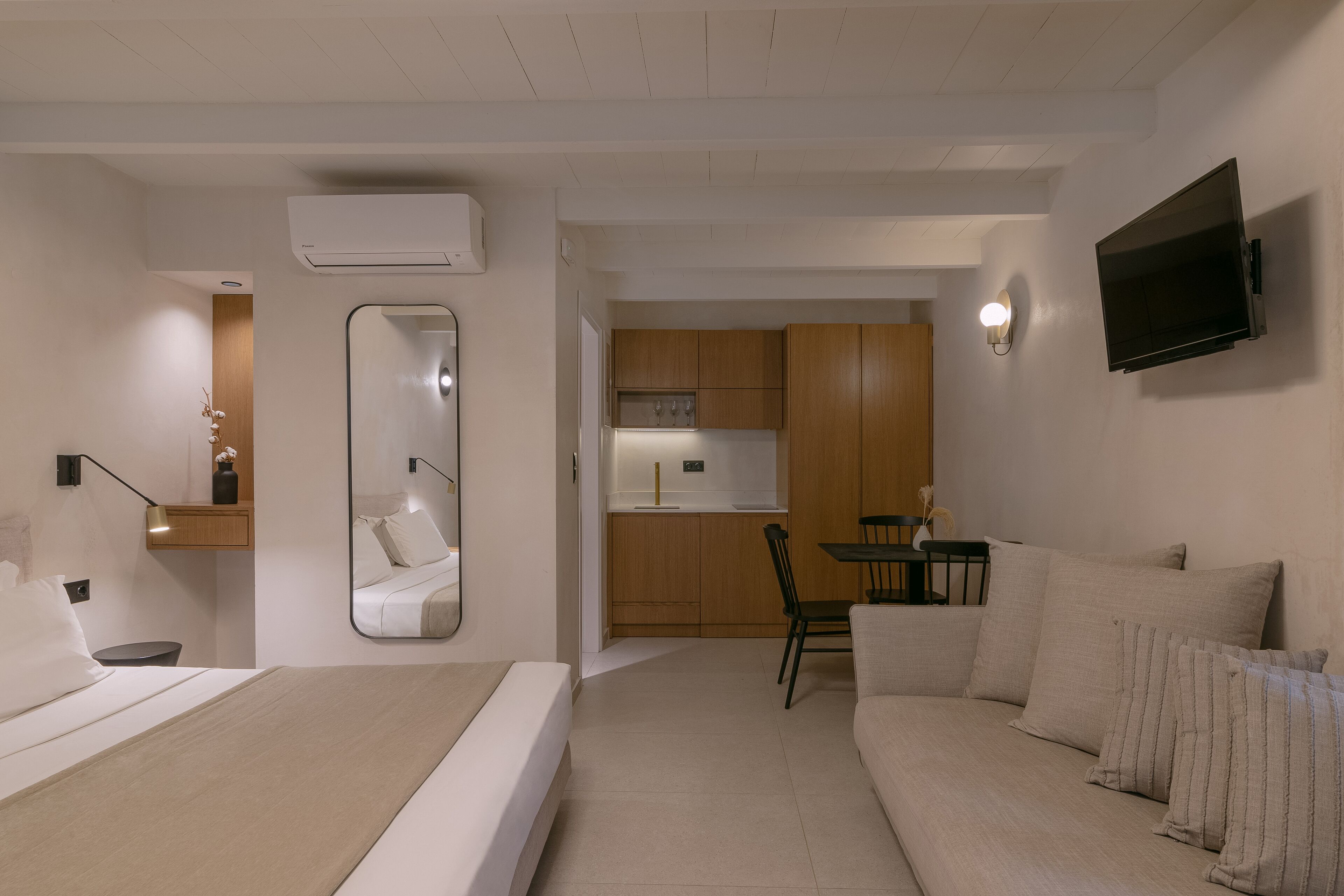Un espacio habitable moderno y funcional con cama, sofá, comedor y kitchenette.