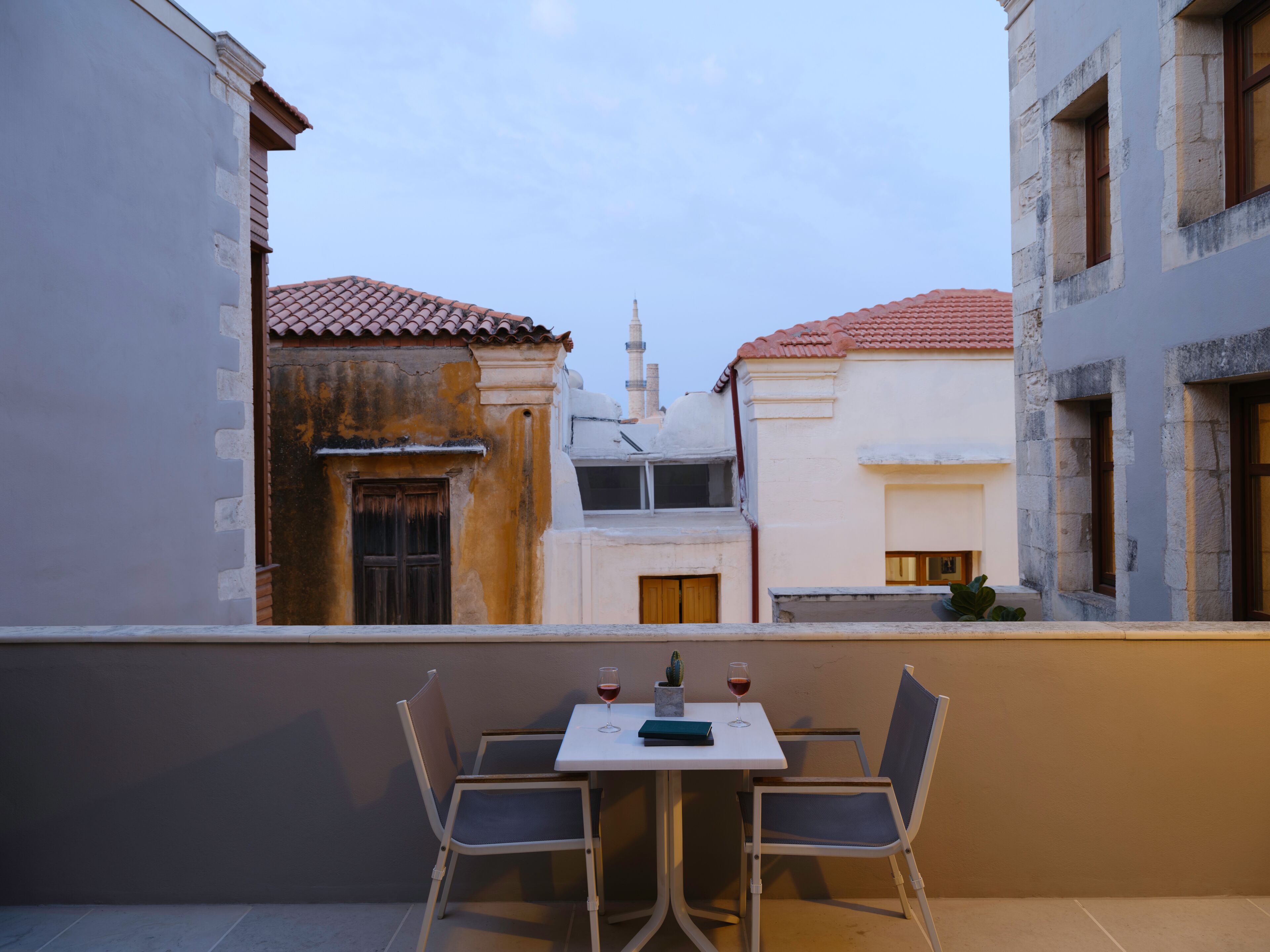 Ein Balkon mit Tisch und Stühlen, mit Blick auf eine Straße mit Häusern.