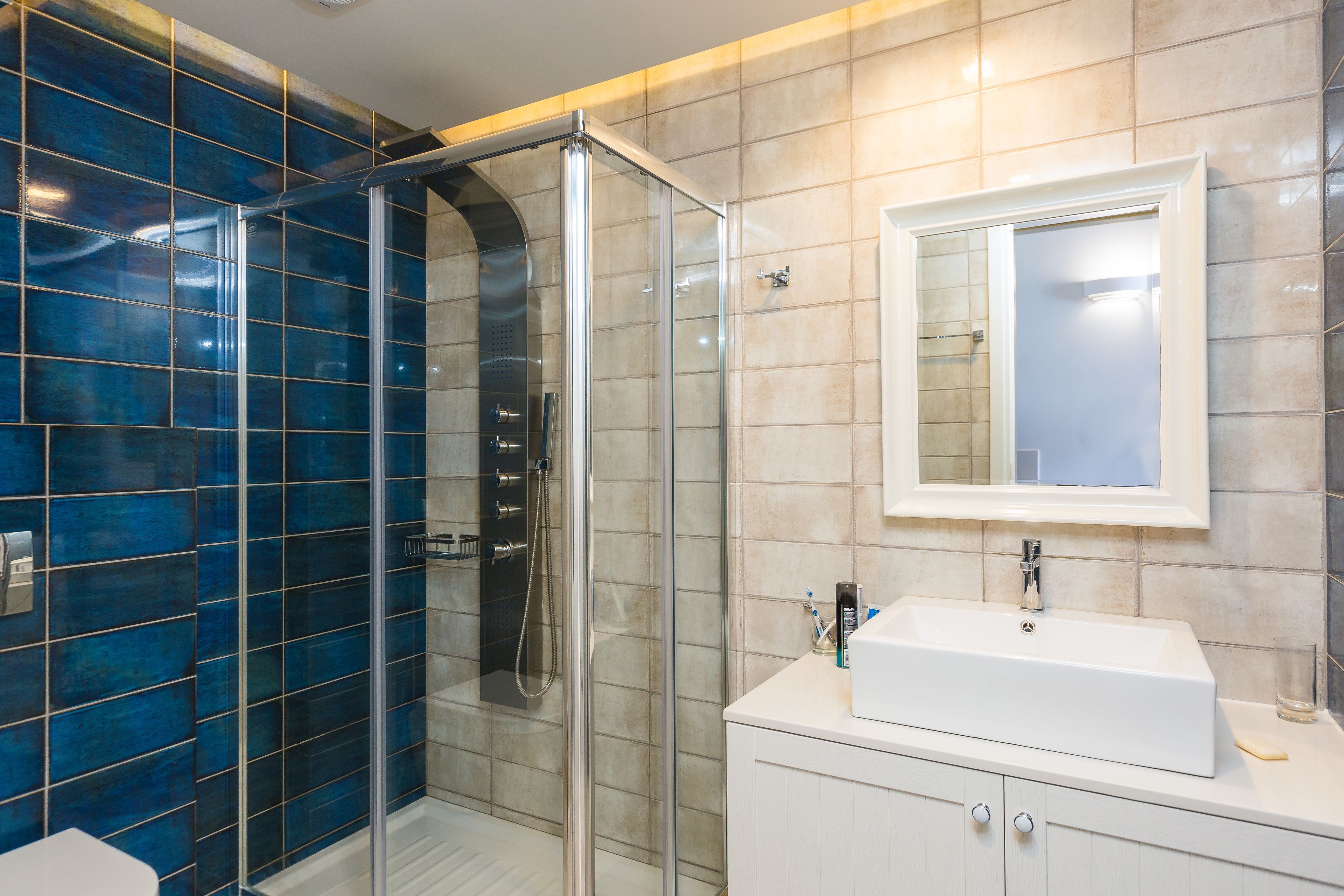 A bathroom with a glass-enclosed shower, a white sink, and a mirror above it.