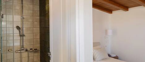 Un dormitorio con cama, mesita de noche, lámpara y techo de madera.
