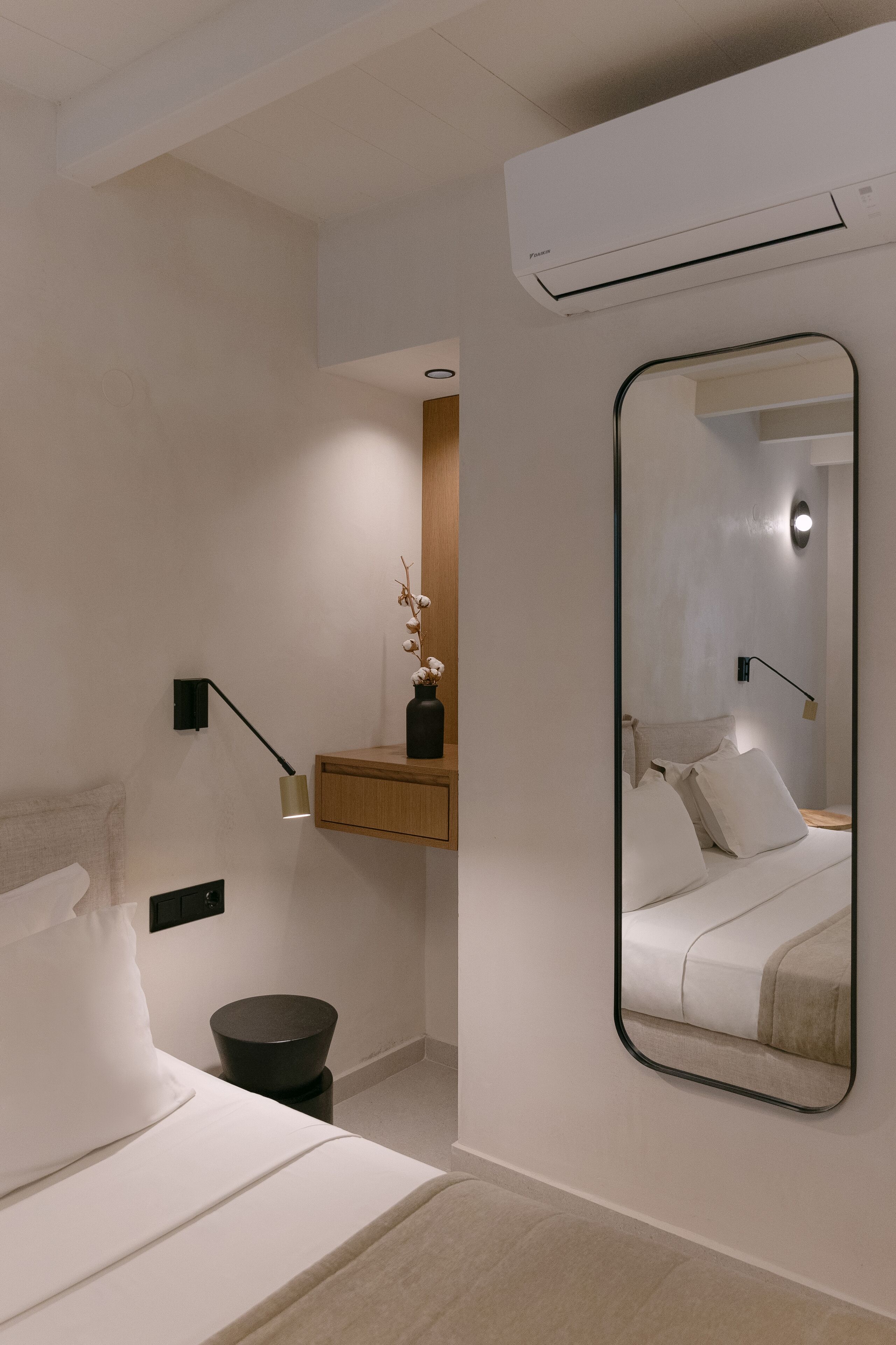 Un dormitorio moderno con cama, mesita de noche, espejo y equipo de aire acondicionado.