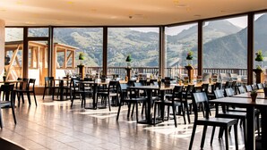 Un restaurante con vistas a la montaña, con mesas y sillas dispuestas para comer.