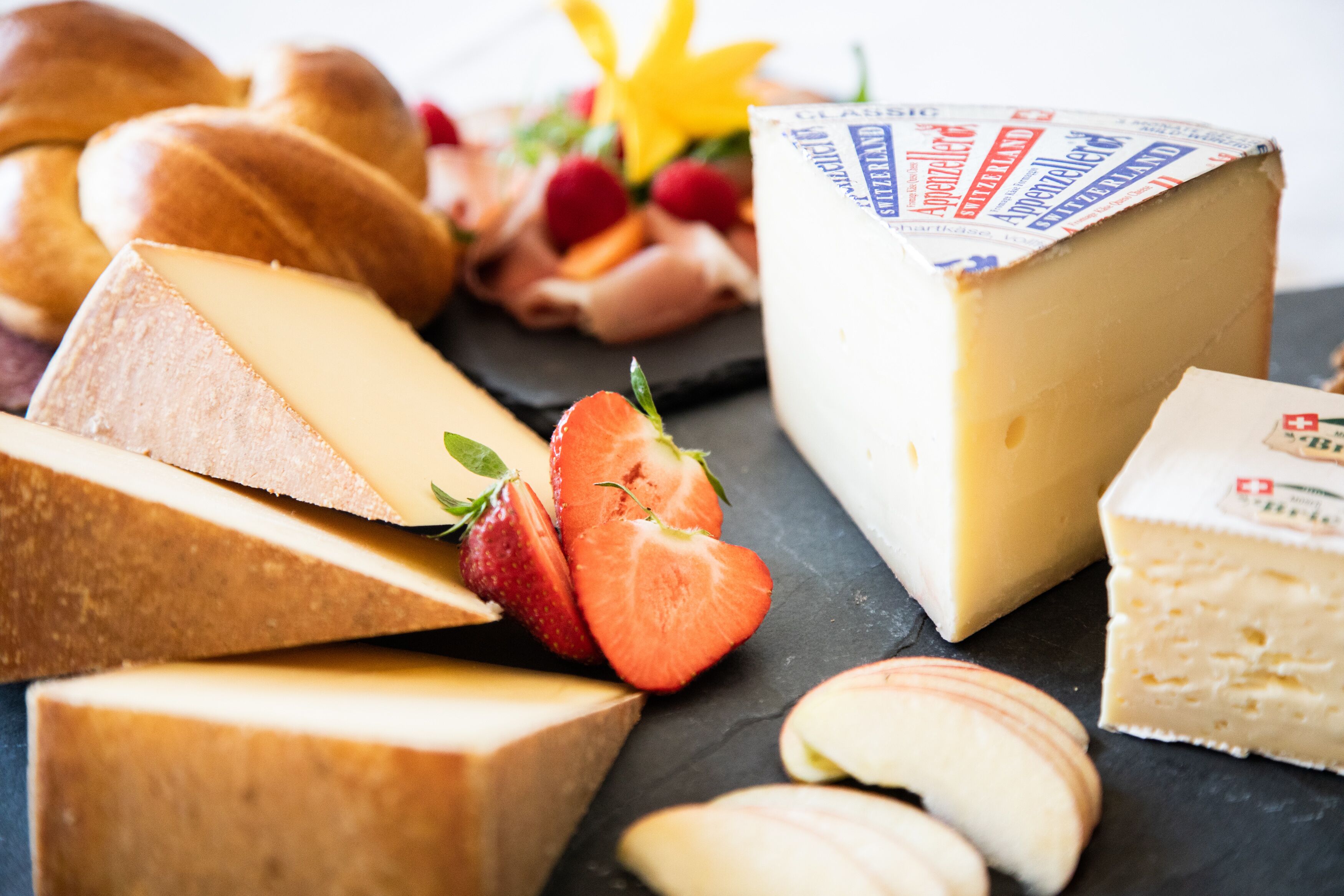 Une sélection de fromages et de fruits présentés sur une planche d’ardoise.