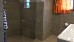 A modern bathroom with a glass shower enclosure, a bathtub, and a toilet. - Hotel Brauerei Frohsinn (Arbon)