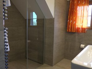 Un baño moderno con cabina de ducha de vidrio, una bañera y un inodoro.