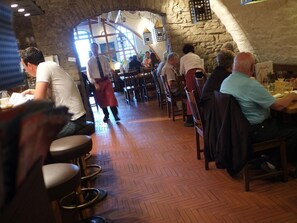 Um restaurante com paredes de pedra, mesas e cadeiras de madeira.