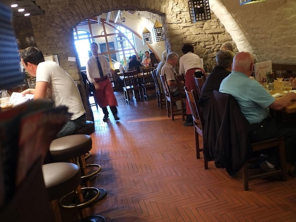 Un restaurante con paredes de piedra, mesas y sillas de madera.