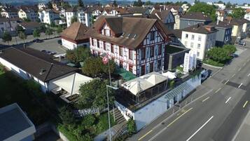 A residential area with a prominent two-story house featuring a gabled roof and a balcony.