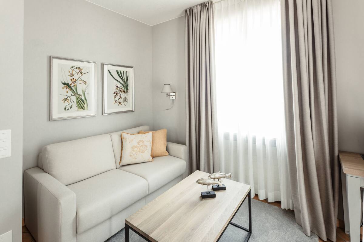 Ein modernes Wohnzimmer mit einer Couch, einem Couchtisch und zwei gerahmten Pflanzenbildern an der Wand.