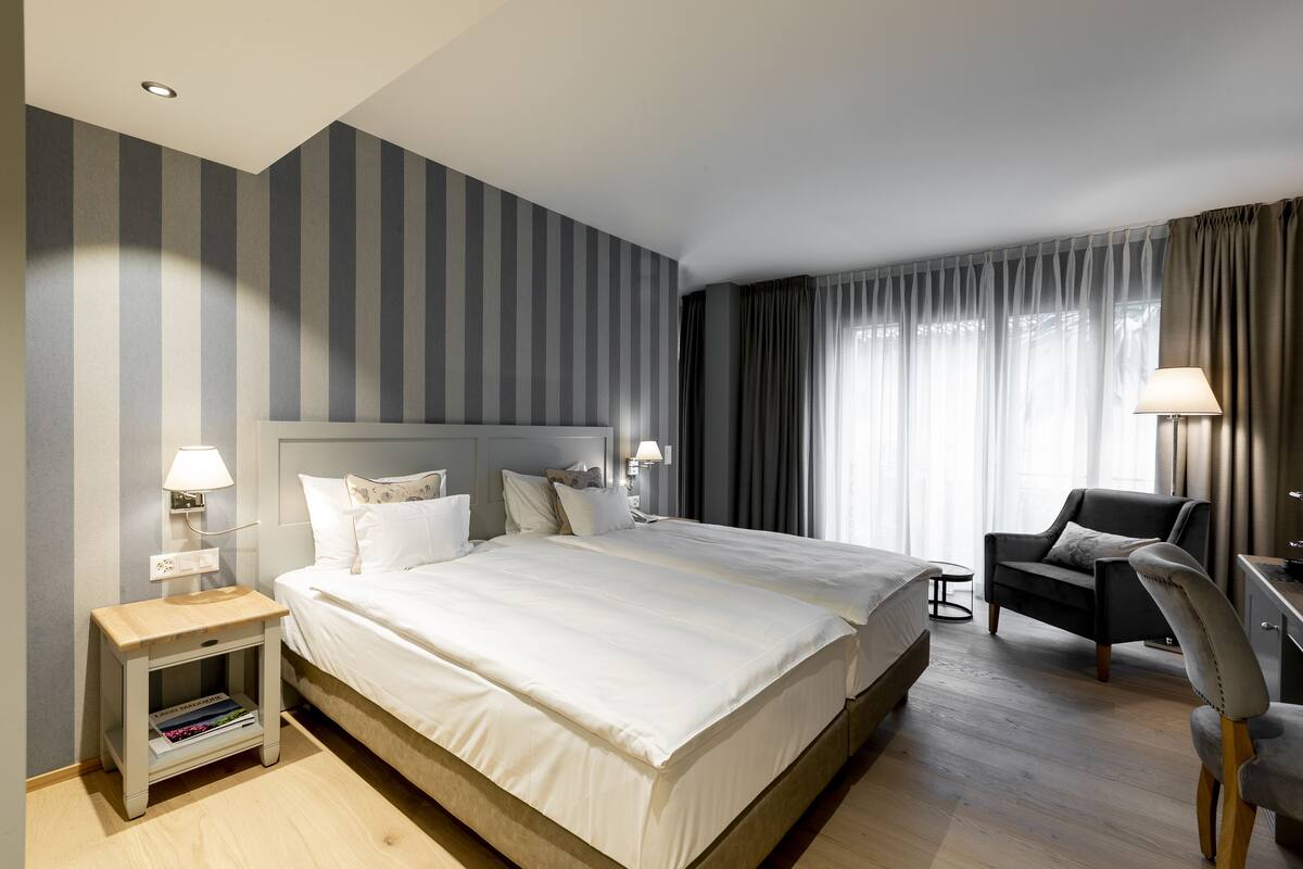 Ein Hotelzimmer mit einem großen Bett, Nachttischen, einem Schreibtisch und einem Sessel.