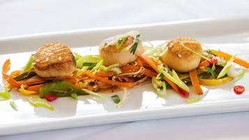 A white rectangular plate with three scallops and a variety of vegetables.