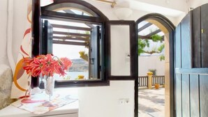 Um quarto com janela, um vaso com flores e vista para o exterior.