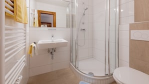 A modern bathroom with a glass-enclosed shower, a white sink, and a toilet. - Haus Margareth (Wagrain)