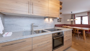 A modern kitchen with wooden cabinets, a stainless steel sink, and an oven. - Haus Margareth (Wagrain)