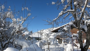 A snow-covered landscape with a wooden fence, bare trees, and a building with a sloped roof. - Haus Margareth (Wagrain)