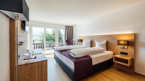 A modern hotel room with a large bed, a desk, and a balcony with a view.