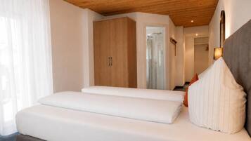 Een slaapkamer met een houten plafond, een bed met wit beddengoed, een kledingkast en een spiegel.