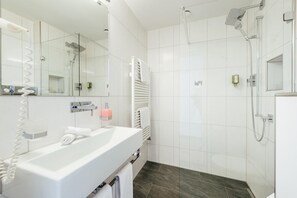 Une salle de bain moderne avec une douche à parois de verre, un lavabo blanc et un porte-serviettes.