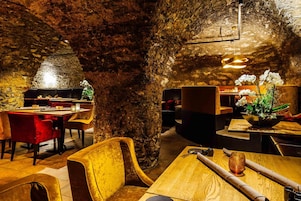 Un restaurante con una decoración rústica que presenta paredes de piedra vista, mesas de madera y sillas tapizadas en rojo.