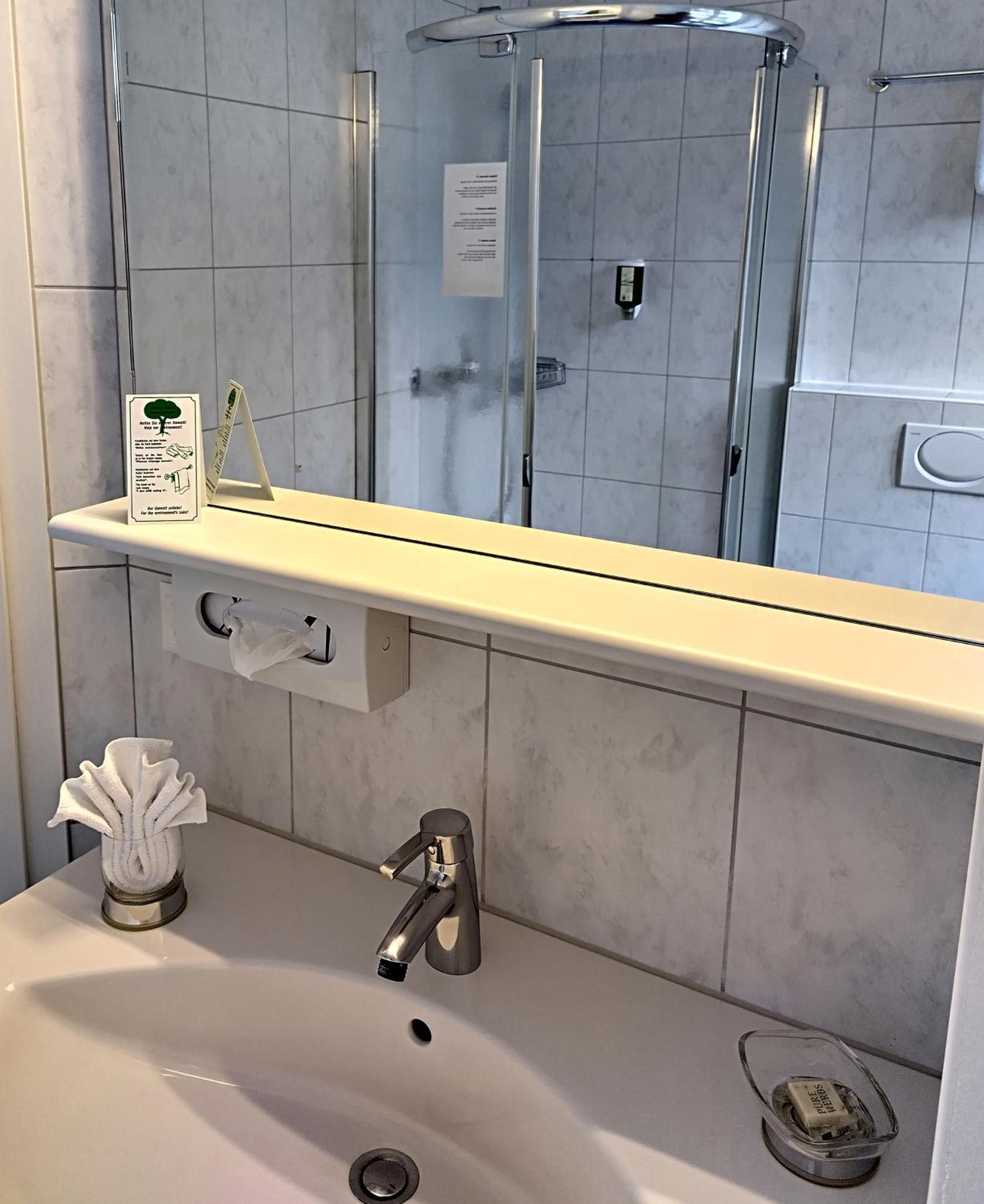 Une salle de bain équipée d’un lavabo, d’un miroir et d’une douche à parois en verre.