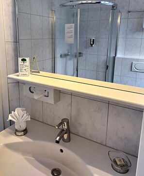 Une salle de bain équipée d’un lavabo, d’un miroir et d’une douche à parois en verre.
