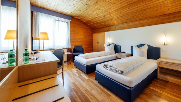 A hotel room with two beds, a desk, and a chair.