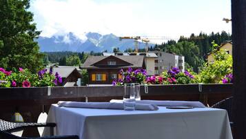 Une table dressée pour deux personnes, avec une vue sur les montagnes en arrière-plan.