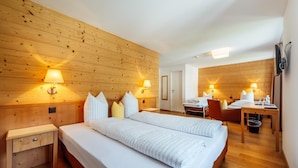 A hotel room with a large bed, bedside tables, a desk, and a chair.