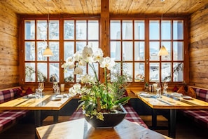 A restaurant with wooden interiors, large windows, and a table with a floral centerpiece.