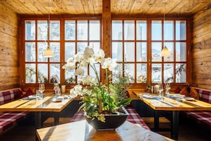 Un restaurante con interiores de madera, ventanas amplias y una mesa con un centro de mesa floral.