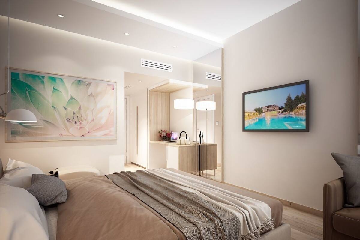 Quarto de hotel moderno com uma cama grande, uma escrivaninha e um banheiro com um espelho amplo.