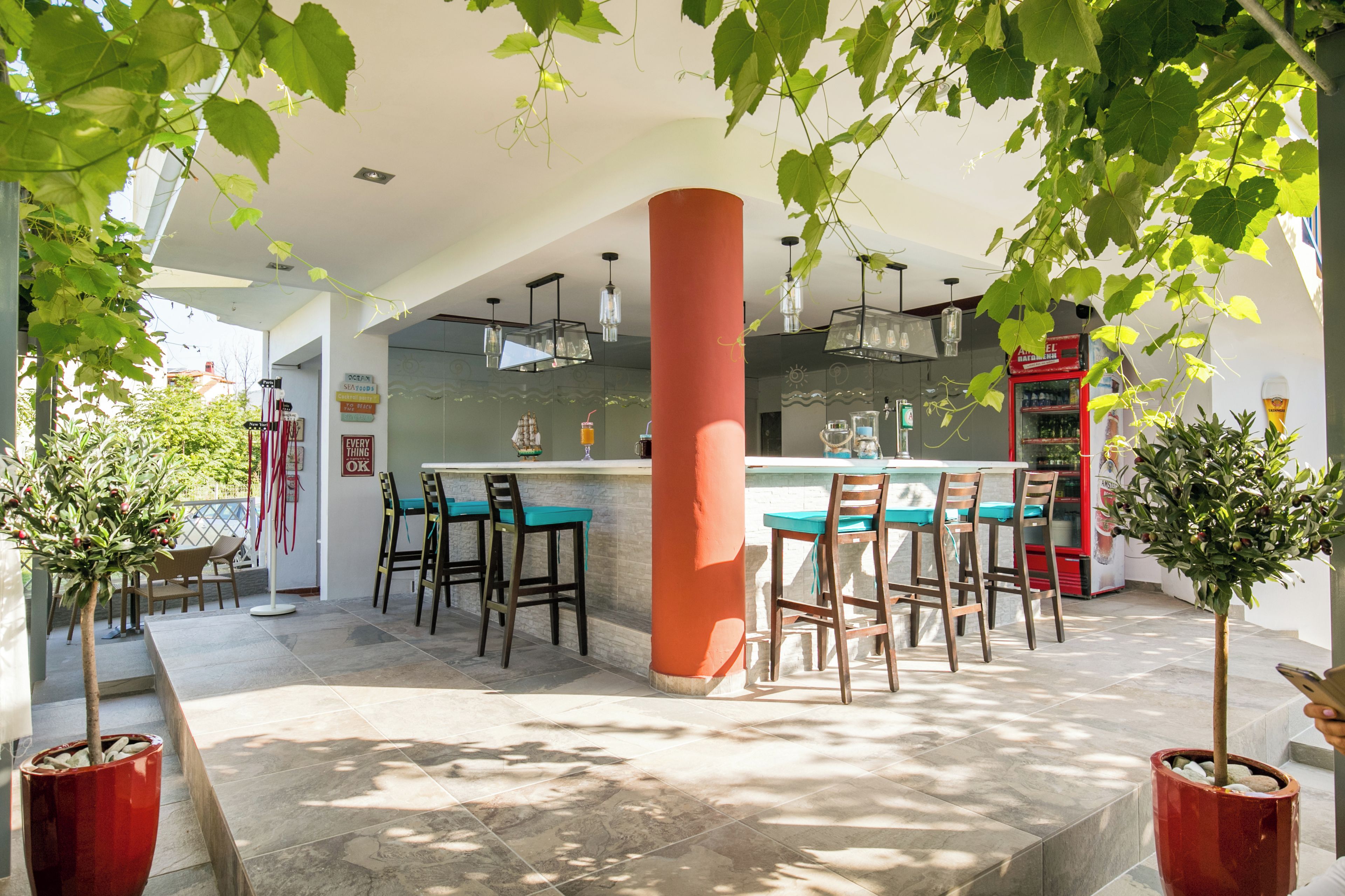 A modern kitchen with a central island, bar stools, and potted plants.