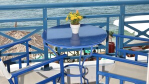 A blue outdoor seating area with a table and chairs, overlooking the sea. - Thalassies (Thasos)
