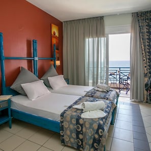 A hotel room with two beds, a balcony with a table and chairs, and a view of the sea. - Thalassies (Thasos)