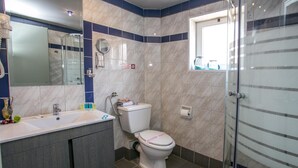 Een moderne badkamer met een wit wastafelmeubel, toilet en een douchecabine met glazen wanden.