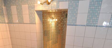 A woman in a bathtub with a control panel, a bench, and a tiled wall with a patterned design.
