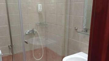 A bathroom with a glass shower enclosure, a white sink, and tiled walls.