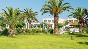 Ein Hotel mit Gartenanlage, Palmen und Schwimmbad.