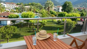 Ein Balkon mit einem Holztisch, zwei Gläsern mit Trinkhalmen und einem Strohhut.
