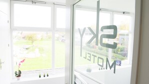 A room with large windows, a view of a green landscape, and a sign with the text 'SKY HOTEL'. - Sky Design Motel (Oberriet)